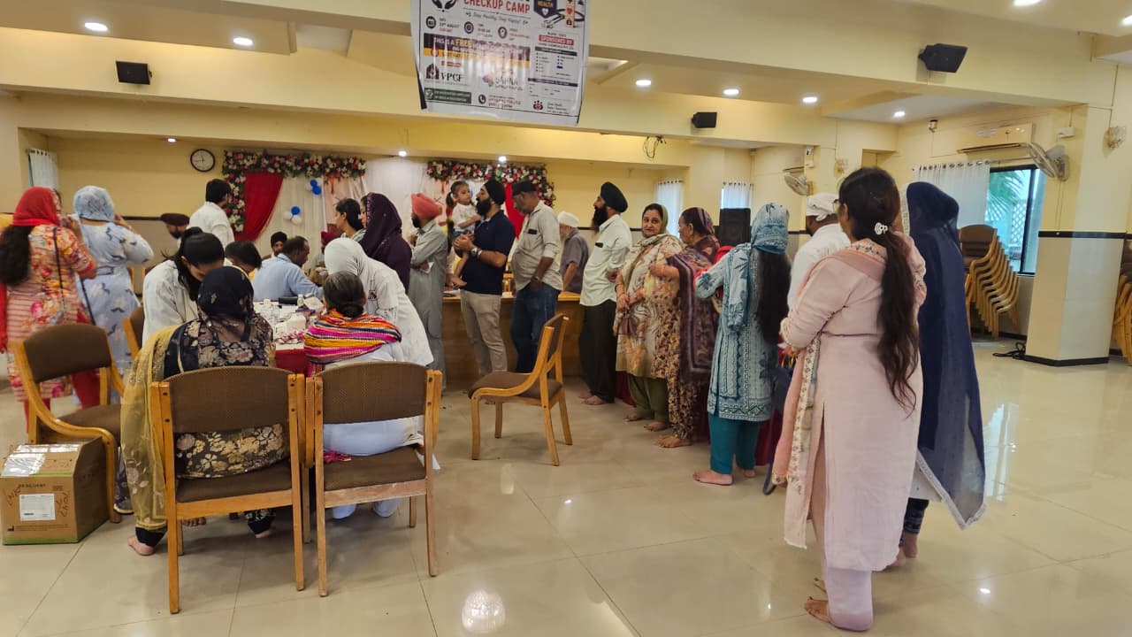 Attendees gathered near the blood testing area beneath the Health Checkup Camp banner in Vapi